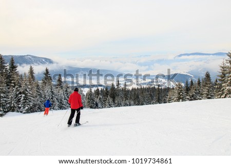 Two men skiing downhill with a view on the mountain