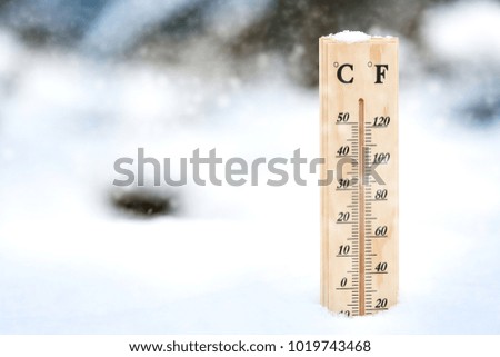 Falling snow in winter and a thermometer.
