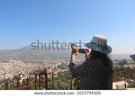 Female traveller make a panoramic photo of the old city in a nice day