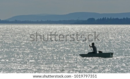 Fisherman in a boat rowing in lake Balaton, in Hungary during sunset 