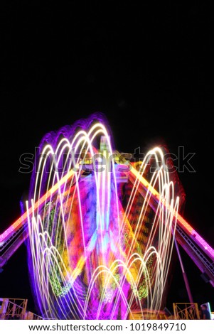Fairground amusement park rides in motion at night, long exposure picture with blurred lights - Bridgwater Fair, UK