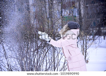 the girl throws snow at the top, in the winter in the city Park