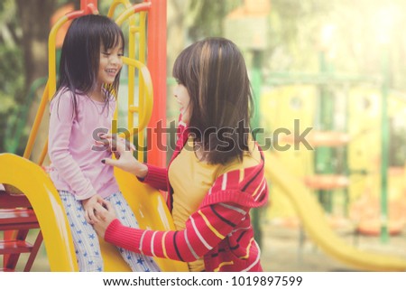 Asian mother and daughter having fun playing slides