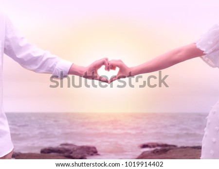 hands of couple making heart sign