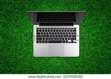 Top view of laptop on green grass.