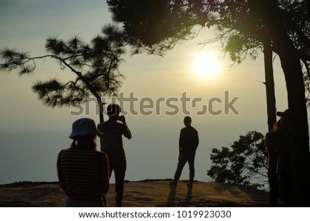 siluate people take a picture on a cliff and sunset time 