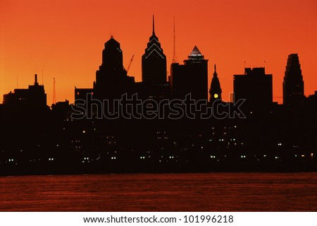Urban skyline silhouetted by sunset