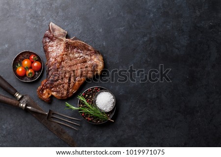 Grilled T-bone steak on stone table. Top view with copy space Royalty-Free Stock Photo #1019971075