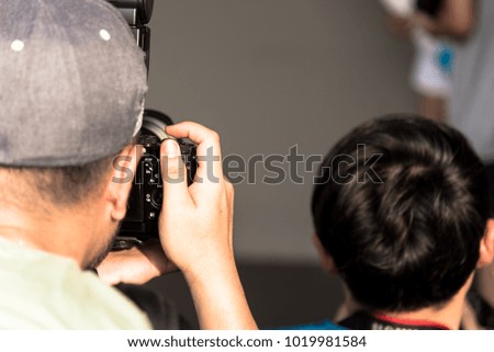 A photographer man has taking and focusing a picture of businesswoman isolated and grey background with business concept.
