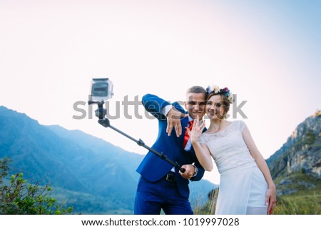 Beautiful young wedding couple making selfie and kissing on the background of mountains