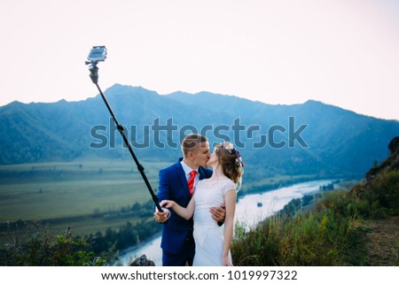 Beautiful young wedding couple making selfie on the background of mountains and river