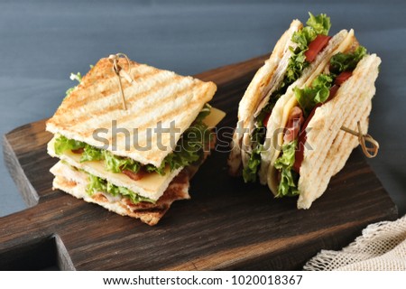 sandwich with bacon, chicken breast and lettuce on wooden background