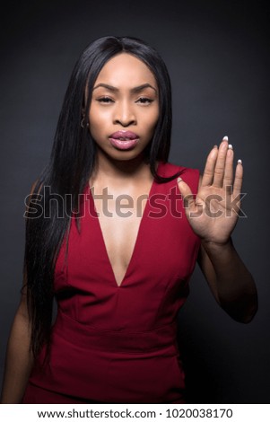 Black female model on a dark background with stop or halt expressions.  She is holding her palms up.