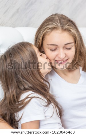daughter kisses her mom on the bed
