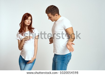  pregnant woman looks at the man, young couple on a light background                              