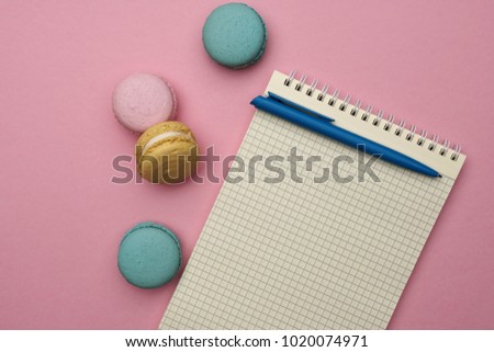 Female styled workplace with notebook, pen and pastel french macaroons. Flat lay style, place for text