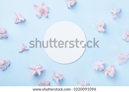 Wedding mockup with white paper list and pink flowers on blue table from above. Beautiful floral pattern. Flat lay style.