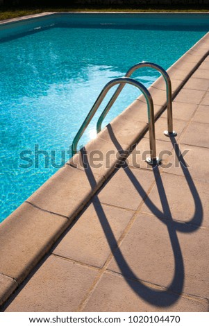 Graphic semi-abstract shape of outdoor swimming pool ladder shadows