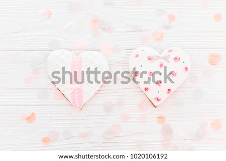 two pink cookie hearts  on white rustic wooden background with confetti flat lay in soft light. happy valentine's day. happy mother's women's day greeting card. space for text