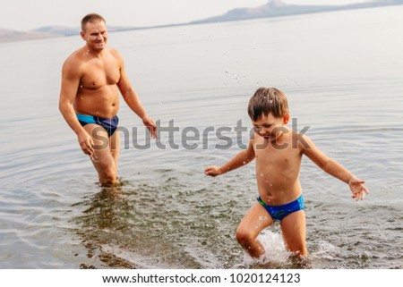 father and child playing on the lake. man with child playing in the water on the beach, emotional photos, summer day