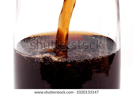 closeup on cola being poured into glass against white  background