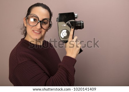 Portrait of woman with big glasses holding old vintage film camera