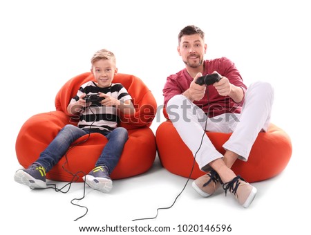 Cute boy with father playing video game on white background