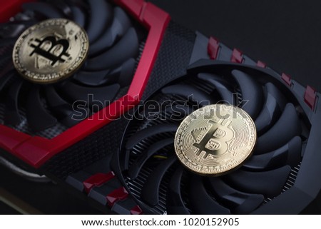 cryptocurrency mining concept closeup with golden bitcoins on top of a computer performant video card black fans Royalty-Free Stock Photo #1020152905