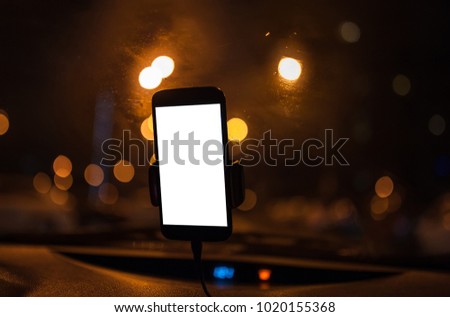 Mobile smart phone with map gps navigation application with planned route on the screen. Blurred car interior on the background with city light in the night.