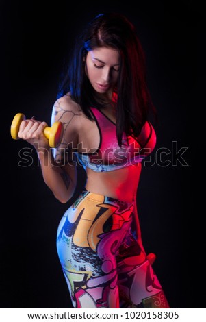 Sport girl in colorful leggings on the black background.