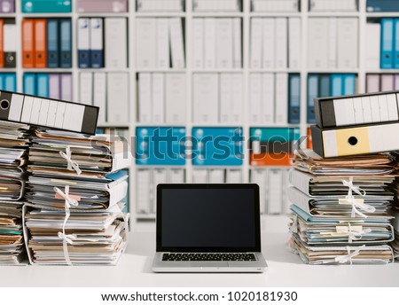 Piles of paperwork in the office and laptop on the desktop Royalty-Free Stock Photo #1020181930