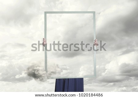 surreal moment of a woman hiding behind a picture of clouds equal to the landscape