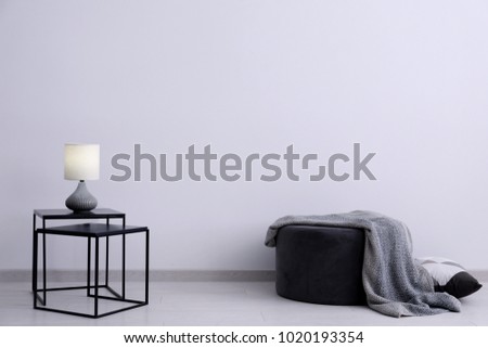Living room interior with elegant table and pouf near wall