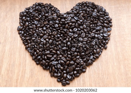 Roasted coffee beans in heart shape on red-grey wooden background, Isolated picture or texture