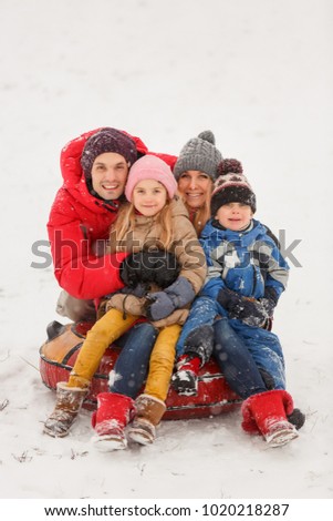 Picture of happy family with daughter and son sitting on tubing in winter