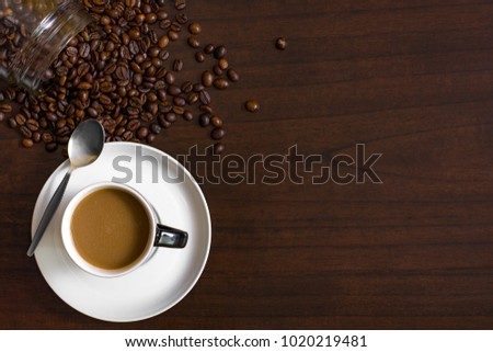Cup of coffee from above, lay flat image, with coffee beans on wood table. Royalty-Free Stock Photo #1020219481