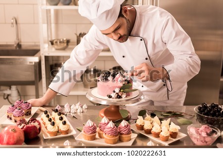 portrait of confectioner decorating cake in restaurant kitchen Royalty-Free Stock Photo #1020222631