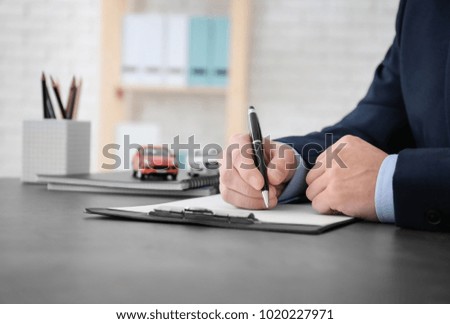 Man filling in car insurance form at table