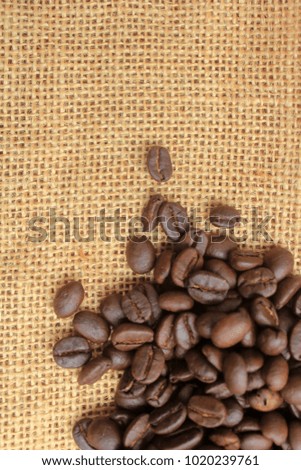 Fresh coffee beans on wood and linen bag, ready to brew delicious coffee.