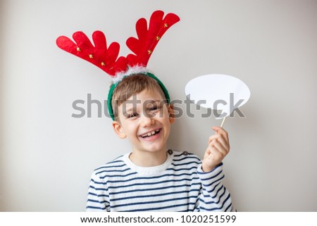 Brown young boy in a festive mood smiling and holding white message bubble
