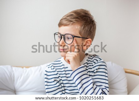 Thoughtful young boy with glasses imagining something