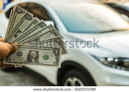 A hand holding dollars on car. A man holding dollars for cash  on car. Money for sales exchange. Photo concept  finances and money.