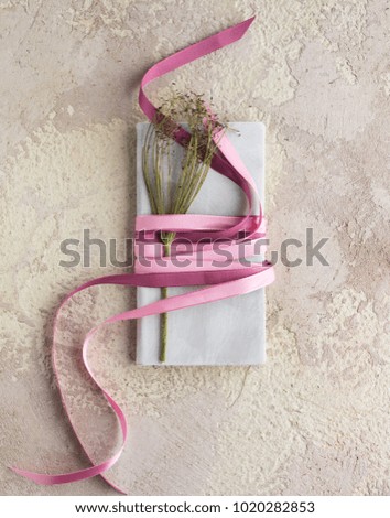 gray notepad with bright pink ribbons on a light background with dill decoration
