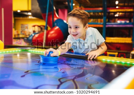 Joyful little boy playing air hockey at Arcade centre Royalty-Free Stock Photo #1020294691