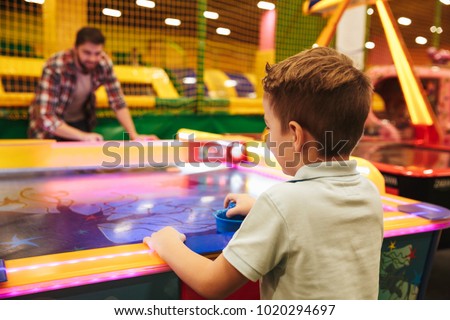 Happy little boy playing air hockey with his dad at Arcade centre Royalty-Free Stock Photo #1020294697