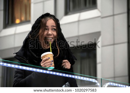 young pretty teenage hipster girl outdoor in winter snow park having fun drinking coffee, warming up happy smiling, lifestyle people concept, very beautiful girl drinks coffee in the street in winter