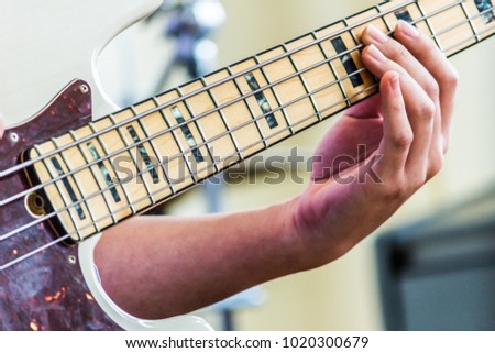 Close up of a bass guitar's hand while the player performs  learning and teaching