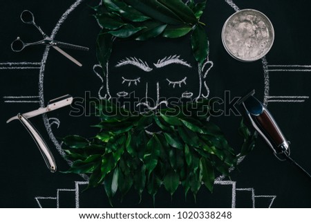 top view of arranged ice cubes in bowl, scissors, razor and drawn picture on blackboard