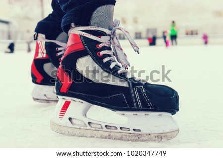 Skater legs at skating rink. Skates black color of. Legs in black pants in ice skating. Amateur sports hobby. old sports hockey skates. on a man's leg. on the ice.