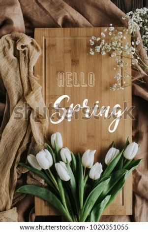 top view of white tulips on wooden board with hello spring lettering